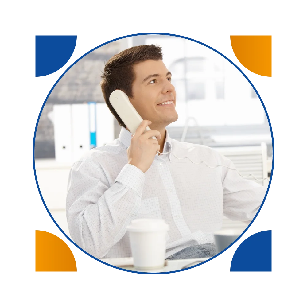 A man sitting at a desk, talking on the phone, while managing house cleaning inquiries