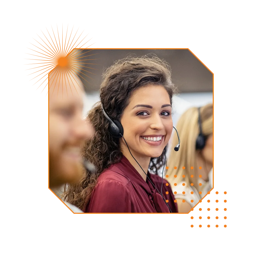 A smiling woman wearing a headset engages with a group of attentive individuals in a professional setting