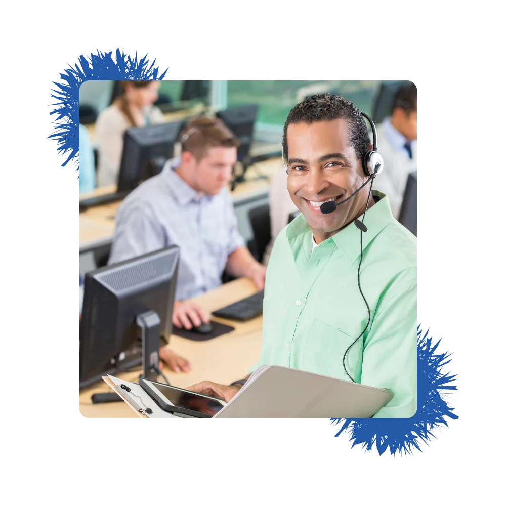 A man wearing a headset is focused on his laptop while working in a call center environment