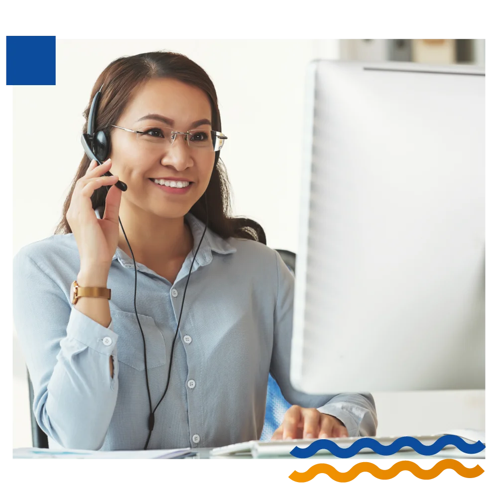 A woman with a headset smiles while engaging with her computer, showcasing a positive and focused work environment