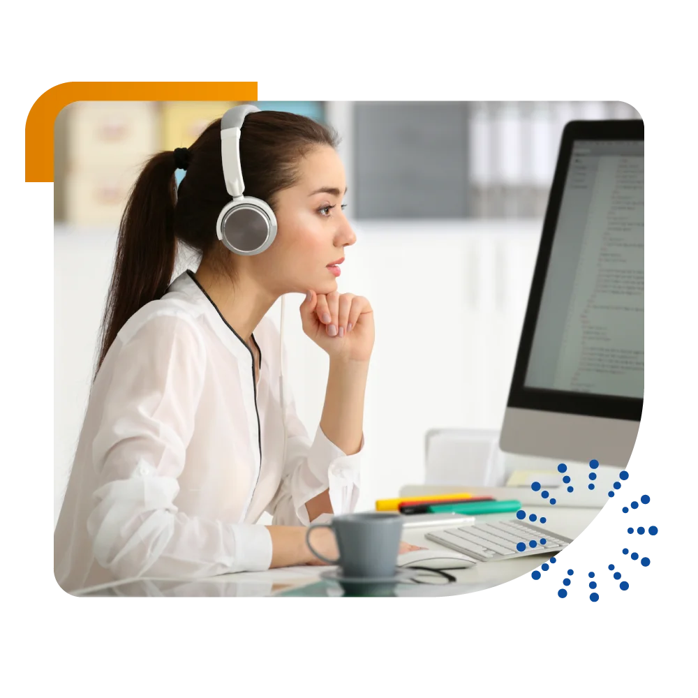 A woman wearing headphones focuses on her computer screen, engaged in her work or entertainment