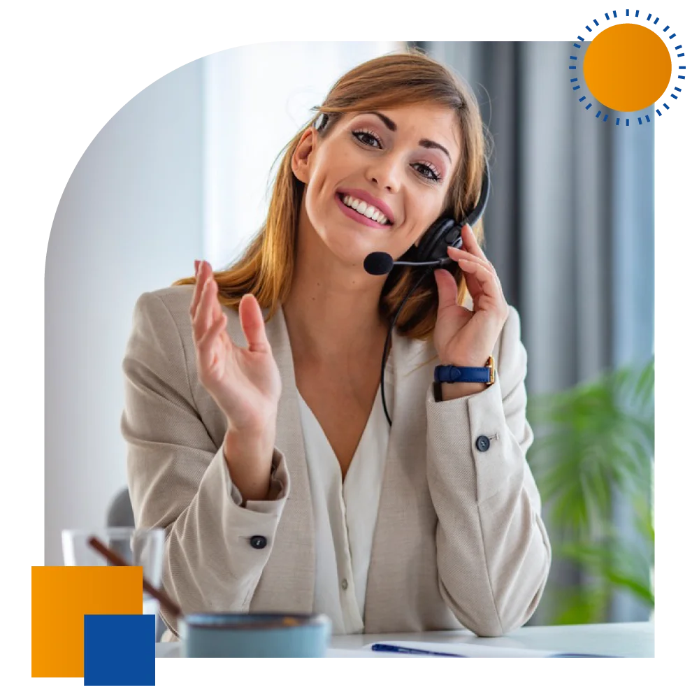 A smiling woman wearing a headset talks on the phone, showcasing a positive and engaging communication style.