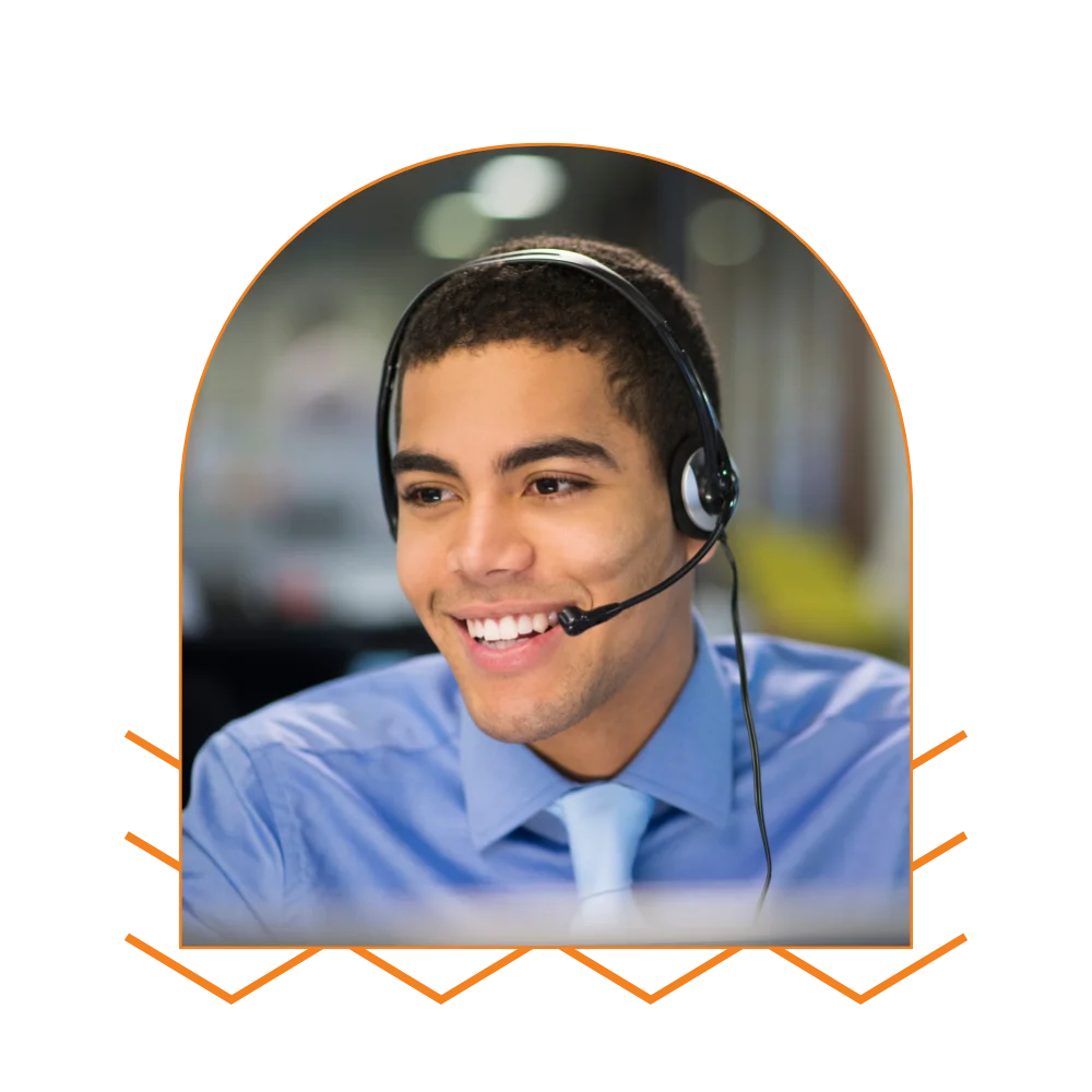 A cheerful man with a headset, actively participating in a call while working at his desk in an office setting