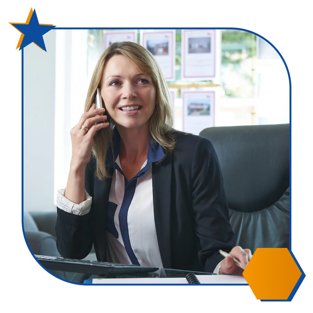 woman at her desk, speaking on a cell phone, demonstrating concentration and engagement in her discussion