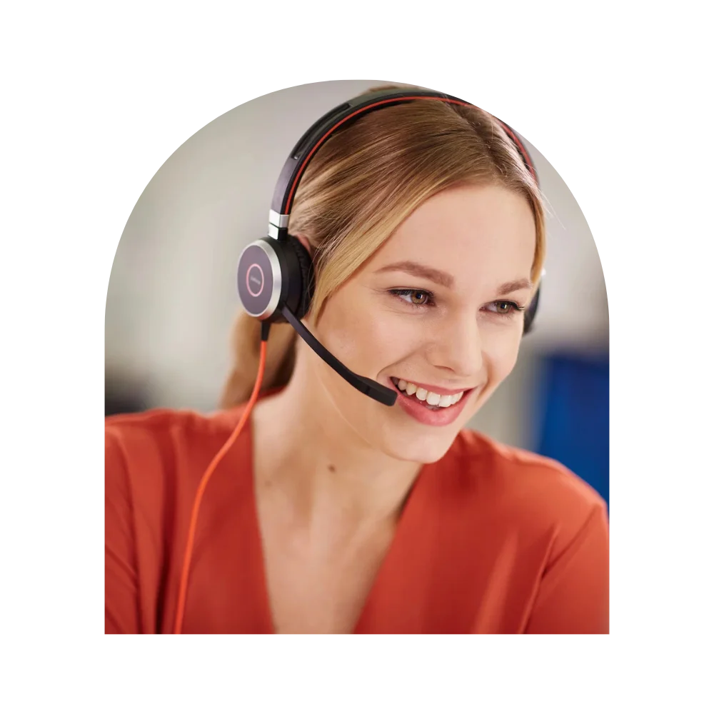 A woman with a headset on, smiling brightly, exuding a sense of joy and engagement in her work environment