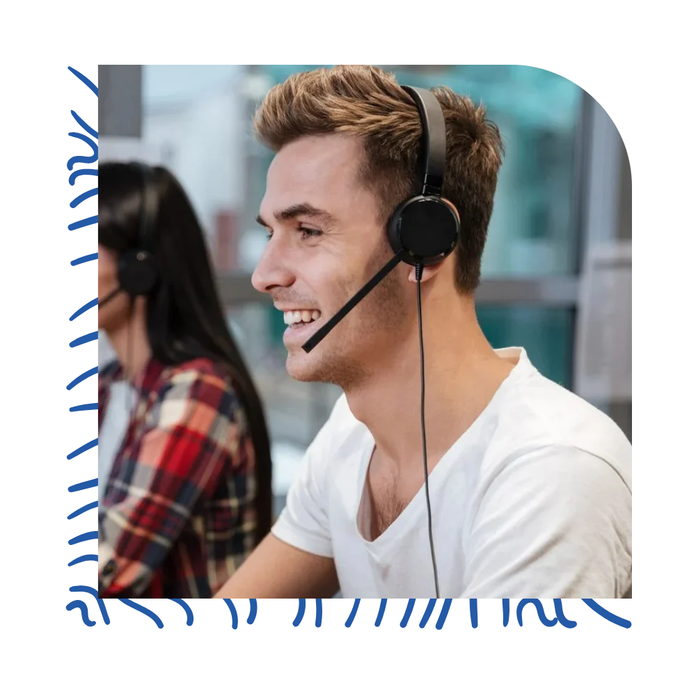 A man with a headset smiles while seated at a desk, exuding a sense of professionalism and engagement